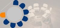 Ein Grauer Kreis mit ringsum dunkelblauen Halbkreisen angeordnet und mittig links ist ein oranger Halbkreis darüber befindet sich eine Linie. Vermutlich soll es einen Tisch mit Sitzplätzen ringsum darstellen und einer Infotafel.